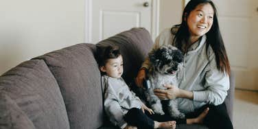 A mom with her dog and toddler on a couch.