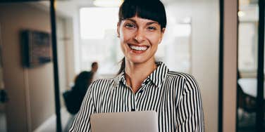 accomplished woman smiling holding computer
