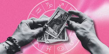 hands holding tarot cards and zodiac wheel