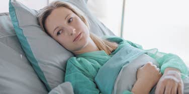 Woman laying in hospital bed after a medical procedure. 