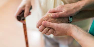 person holding elderly woman's hand