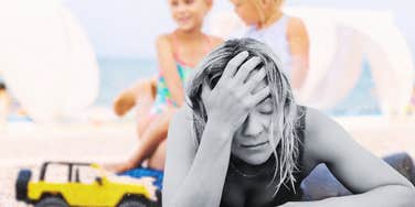 Woman finding parenting disappointing while trying to relax on beach 