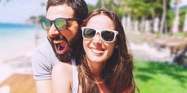 Happy couple by a beach, doesn't realize the damage in their relationship