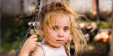 Poor American girl on a swing outside
