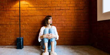 Unhappy single person leaning against wall.