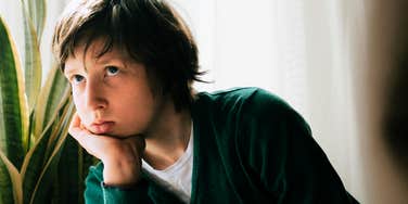 Young boy sitting alone in room, emotionally neglected.
