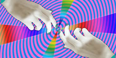 two hands nearly touching in front of swirling colors