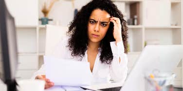 Confused woman at desk, being quiet fired from job. 