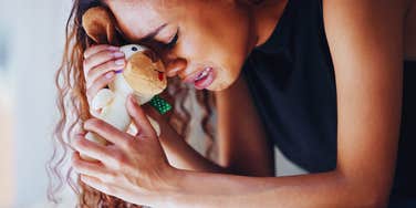 Grieving woman, holding on to babies toy. 