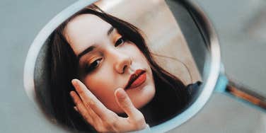 Woman looking in mirror talking through her worst moments. 