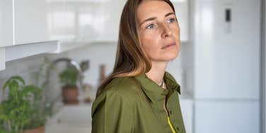Middle-aged woman looking sad in her kitchen.