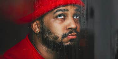 Man looking out at rain ruining his plans, getting signals from the universe.