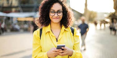 Woman smiling while making money on app on phone. 