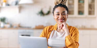 businesswoman smiling while working on laptop at desk in home office