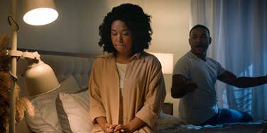 woman sitting on edge of bed during argument with husband