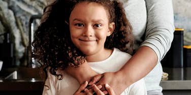 Child raised well, embraced by her mother's arms.