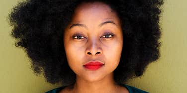 Woman with natural Black hair looks into camera, wondering what keeps her from life of her dreams