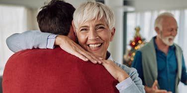 senior parent hugging her adult son at home