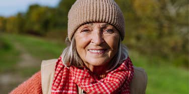 Boomer woman smiling at the camera outside.