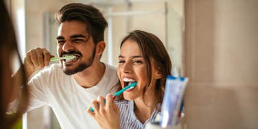 couple brushing their teeth in bathroom together