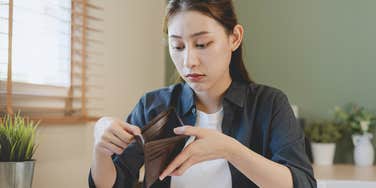 stressed woman looking at her empty wallet after paying fees