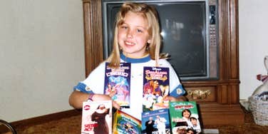 Vintage photo of child anticipating her VHS tapes. 