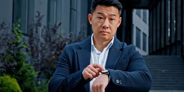 frustrated employee pointing to watch after wasted time