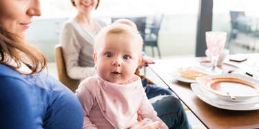 server holding couple's baby while they eat