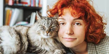 adorable cat snuggling with happy young woman