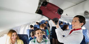 flight attendant putting bag in overhead bin