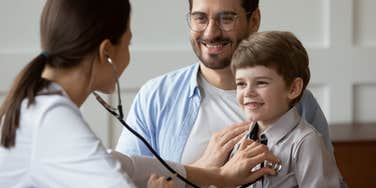 Dad at doctor's appointment with his son laughing because can't fill out forms