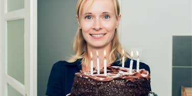 Girlfriend holding the birthday cake she made that her boyfriend didn't like