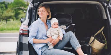 mom holding newborn while sitting in back of car