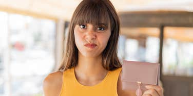 frugal woman holding purse after being raised by broke parents