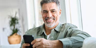 middle aged man smiling holding his phone