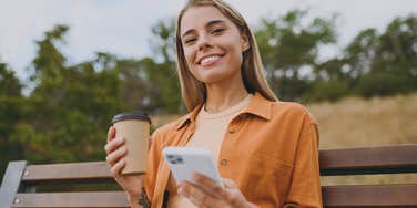 smiling happy woman on her phone drinking coffee