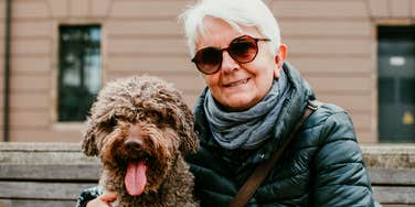 older boomer woman smiling next to her dog