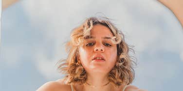 Woman looking into a mirror that is sabotaging her confidence. 