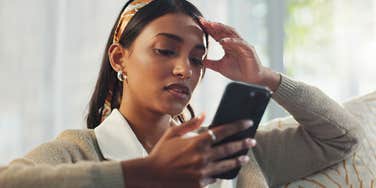 stressed woman on her phone texting to cancel plans