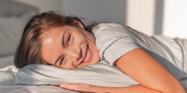 Woman smiling because her sleeping position reveals her personality