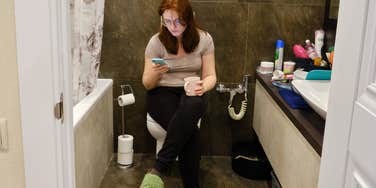 Woman scrolling social media on the toilet