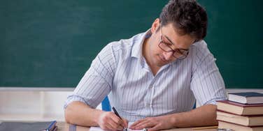 High school principal hand writing thank you notes to school's graduates