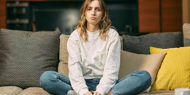 young woman sitting on couch quietly judging