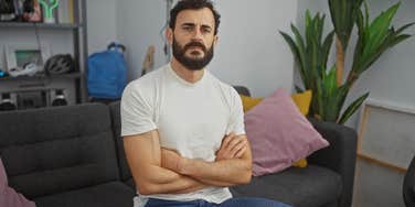 serious man sitting on couch with arms crossed