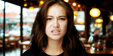 Woman at restaurant, repelled by surprising food habit. 