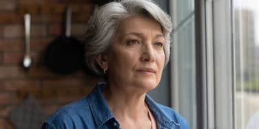 older woman looking exhausted staring out the window