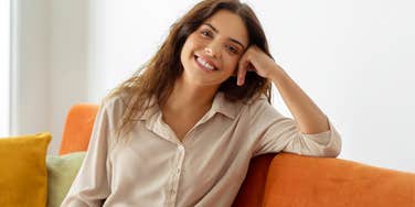 frugal woman sitting on her couch smiling
