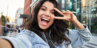 smiling gen z woman making a peace sign for respect