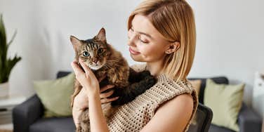 smiling woman holding her judgmental cat