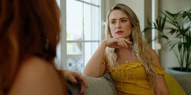 working class woman talking to wealthy friend on a couch